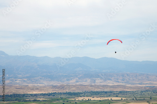 People gliding using a parachute on the background of the blue sky