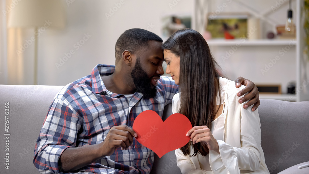 Nice couple touching foreheads and showing paper heart to camera, tenderness Nice couple touching foreheads and showing paper heart to camera, tenderness