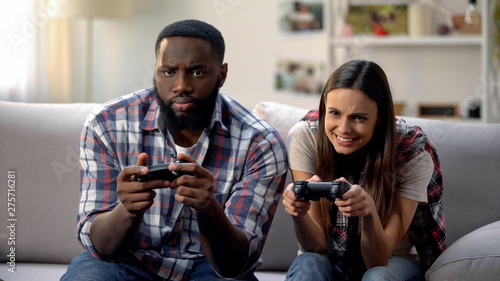 Nice multiethnic couple having fun, playing video game at home, leisure time
