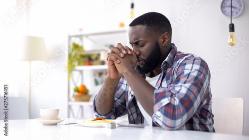 African-American man praying before lunch, thanking God for meal, religion