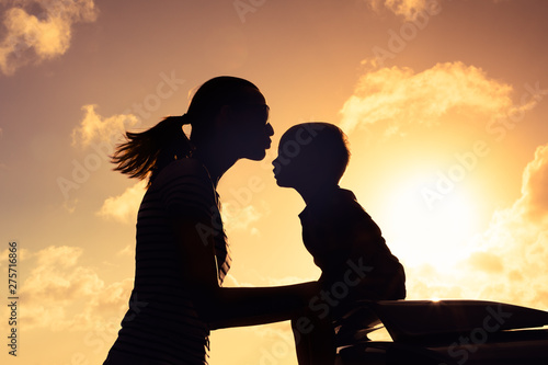 Silhouette of mother kissing her little child. Parent giving child love and affection concept.  