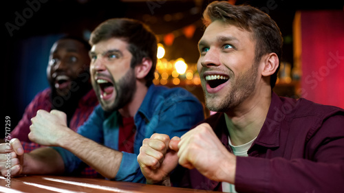 Nervous box fans watching favorite sport on big screen in bar, tournament photo