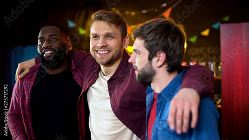 Cheerful multiracial friends hugging, celebrating bachelor party in bar, leisure photo