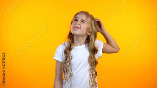 Adorable puzzled girl scratching head, having no ideas, creative child thinking