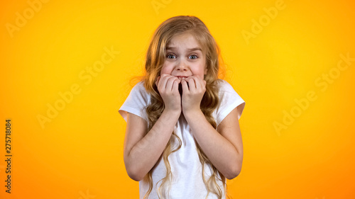 Extremely scared girl biting fingers and looking to camera, childish fears