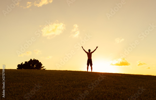 Feeling free. Man facing the sunset with arms up in the air. 