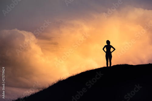 Thoughtful woman standing on mountain watching the beautiful sunset. People, adventure, active lifestyle concept.