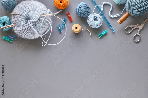 Creative knitting hobby background in pastel colors on grey paper with copy-space