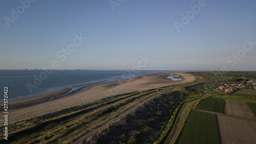 Aerial view of a few houses behind a dike in Holland. Wide beach at low tide in the evening light. Ouddorp Netherland.