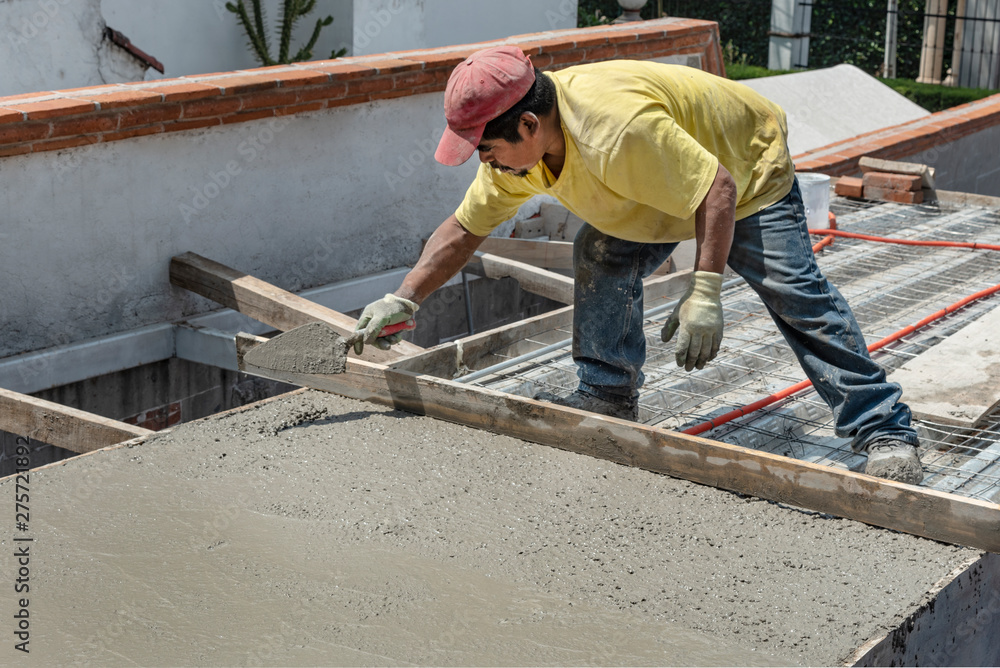 Bricklayer leveling a cement roof. Stretching out to smooth the casted concrete mix Bricklayer leveling a cement roof. Stretching out to smooth the casted concrete mix