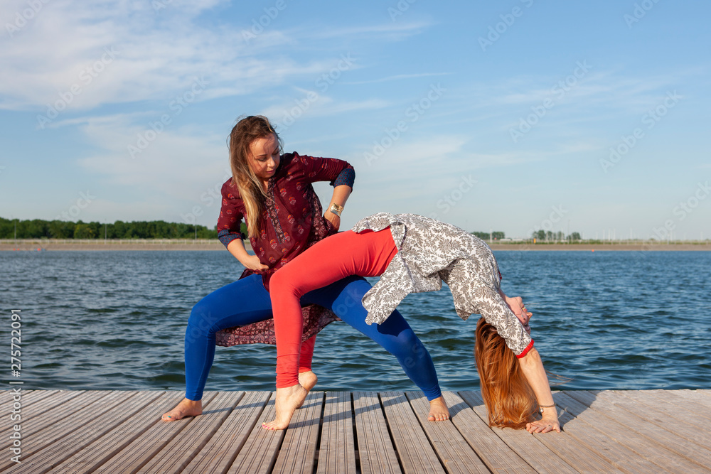 Two women exercising in the park. Young beautiful woman doing exercises together outdoors.
