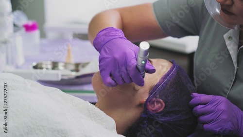 Cosmetologist is applying serum on face of young woman and performing  bb glow treatment