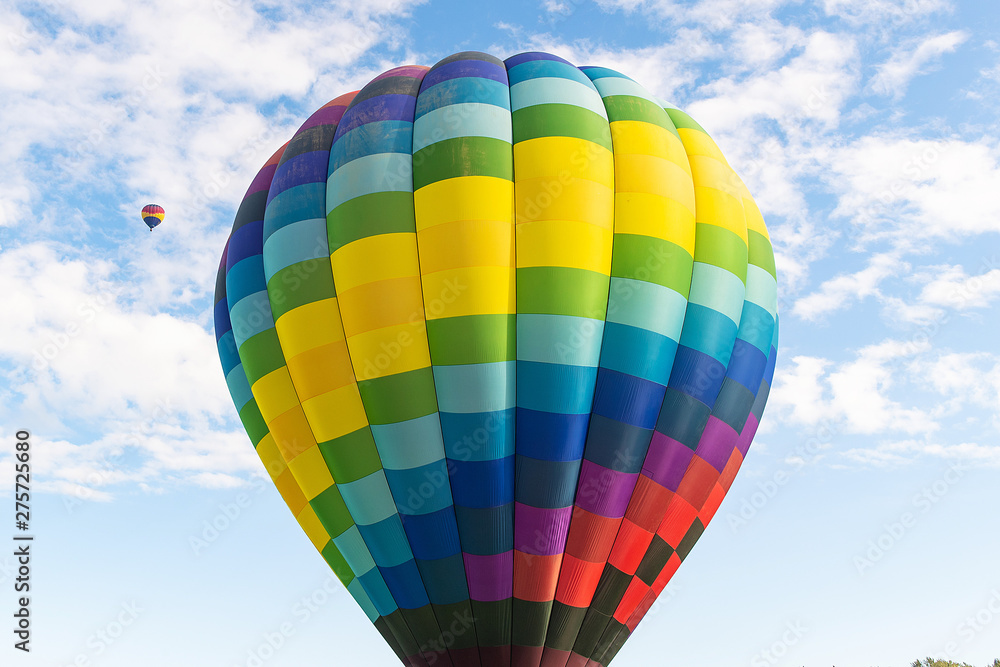 Obraz premium Two hot air balloons floating under vibrant blue sky with puffy white clouds