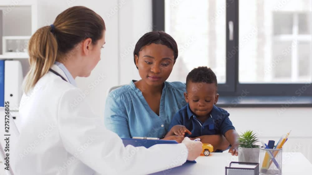 medicine, healthcare and pediatry concept - african american mother with baby son and caucasian doctor with clipboard at clinic medicine, healthcare and pediatry concept - african american mother with baby son and caucasian doctor with clipboard at clinic