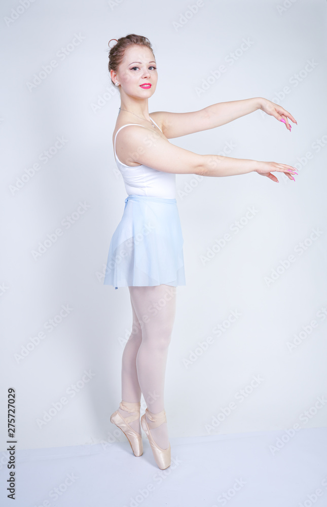 cute caucasian girl in ballet clothes learning to be a ballerina on a white background in the Studio. plus size young woman dreams of being a dancer. cute caucasian girl in ballet clothes learning to be a ballerina on a white background in the Studio. plus size young woman dreams of being a dancer.
