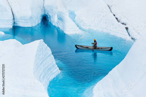 Glacier kayaking over ice cave and deep blue lake in the rain.
