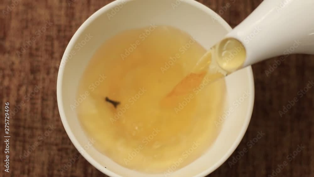 pouring tea from the kettle into the cup pouring tea from the kettle into the cup