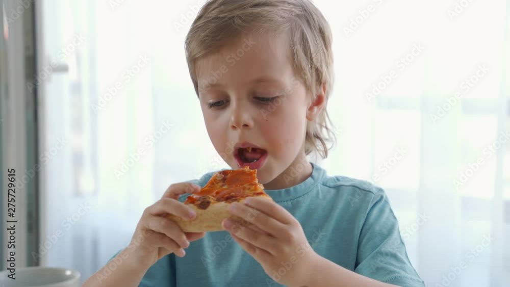 Two little caucasian boys eating pizza at home. Day light Two little caucasian boys eating pizza at home. Day light