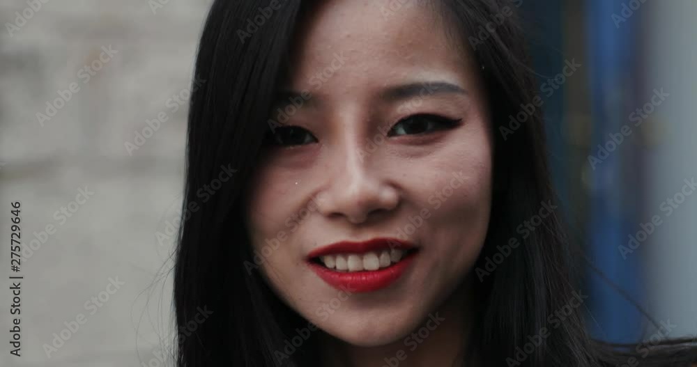 Portrait of the face of charming smiled young Asian girl with red lips while she standing outside. Close up. Portrait of the face of charming smiled young Asian girl with red lips while she standing outside. Close up.