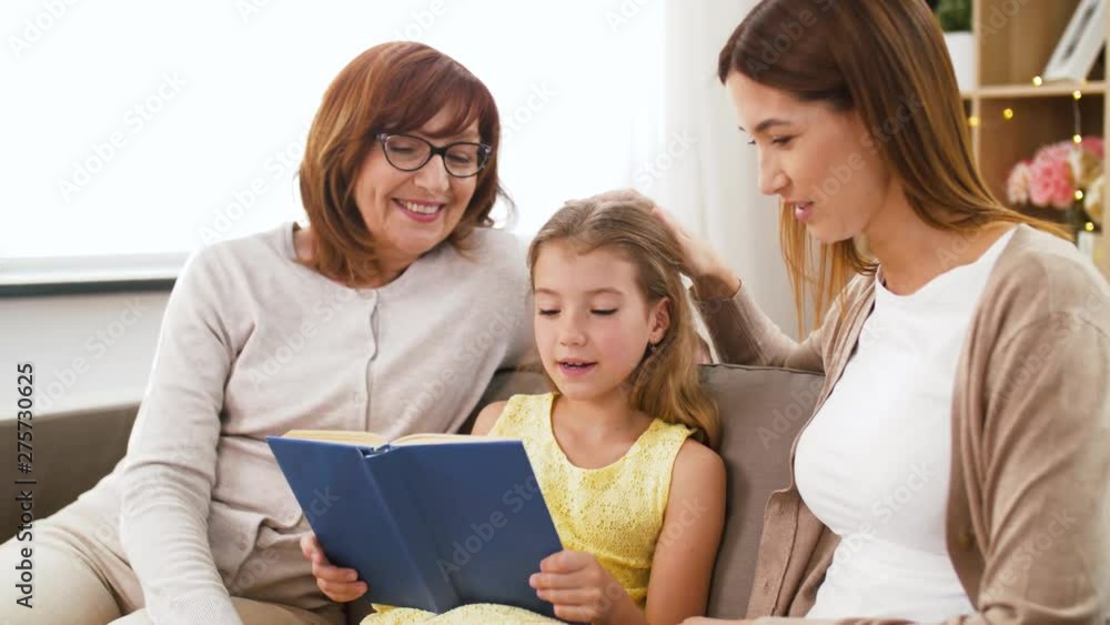family, three generations and technology concept - happy mother, daughter and grandmother reading book at home family, three generations and technology concept - happy mother, daughter and grandmother reading book at home