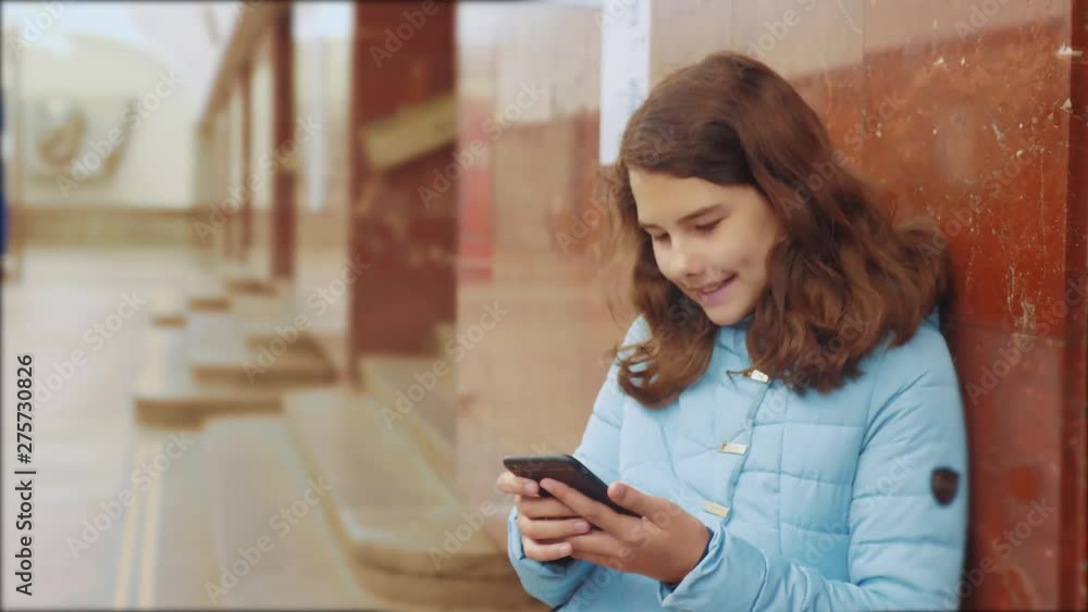 girl teenager in the underground subway rides in the subway waiting for the arrival of train, holds smartphone. lifestyle little girl brunette daughter search the internet on the web social networks girl teenager in the underground subway rides in the subway waiting for the arrival of train, holds smartphone. lifestyle little girl brunette daughter search the internet on the web social networks