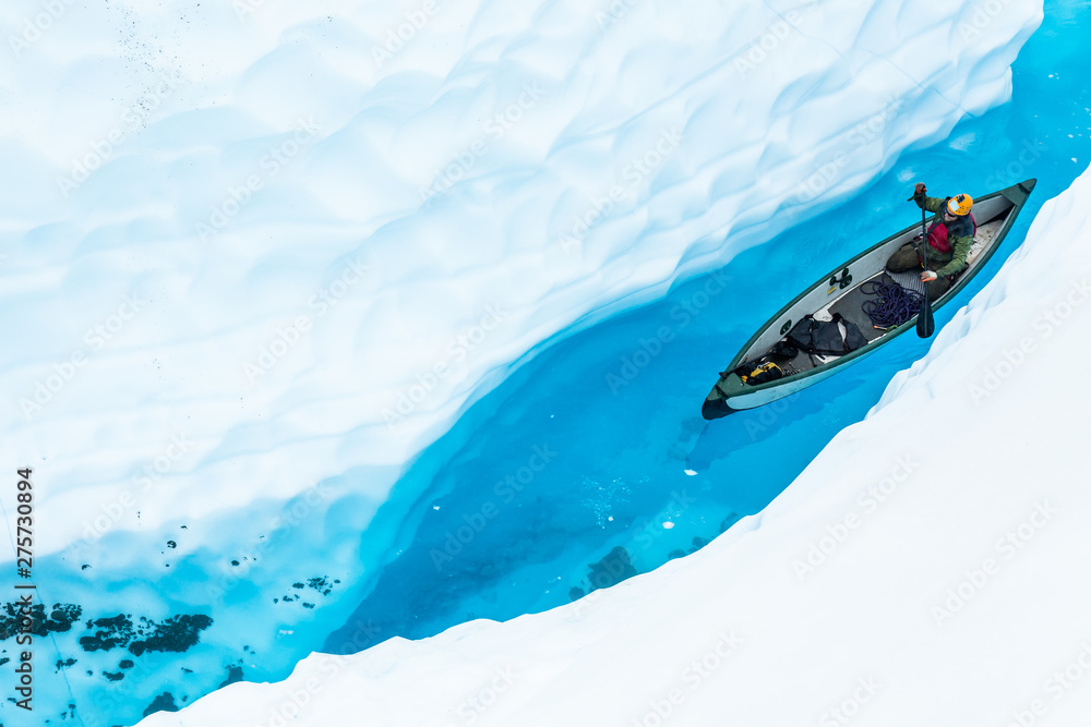 Ice climber canoeing in narrow ice canyon from above. - obrazy, fototapety, plakaty 