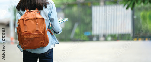 Fotografie, Obraz Back of student girl holding books and carry school bag while walking in school
