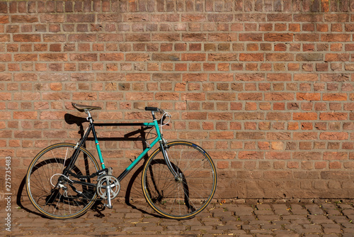 Retro Vintage Commuting Bicycle park and lean against rough old exterior brick wall. Eco friendly and urban lifestyle concept for transportation in city and old town. 