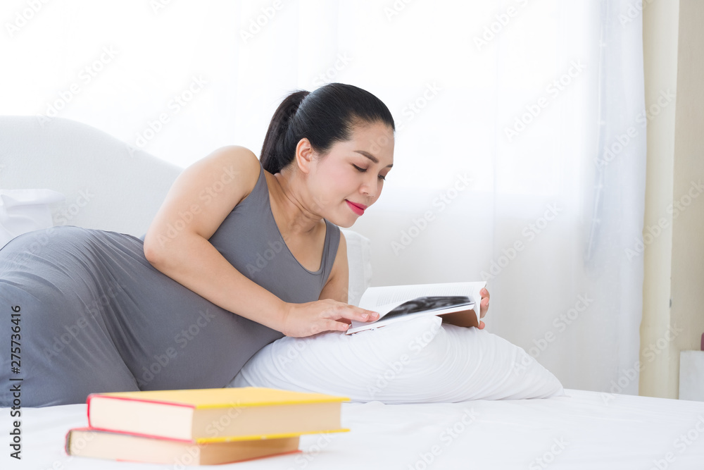 Asia Pregnant woman reading a book on white bed. Mental health care and pregnancy. Asia Pregnant woman reading a book on white bed. Mental health care and pregnancy.