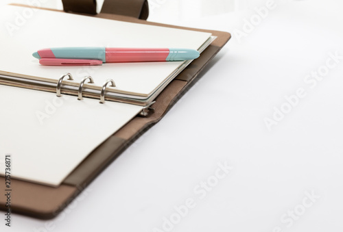 White paper ring organizer book opened on the white background with a fountain pen