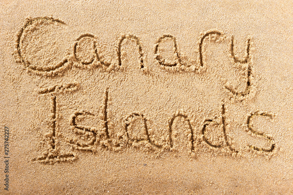 Fototapeta premium Canary islands word written in sand on a sunny spanish island summer beach holiday vacation travel destination sign writing message photo