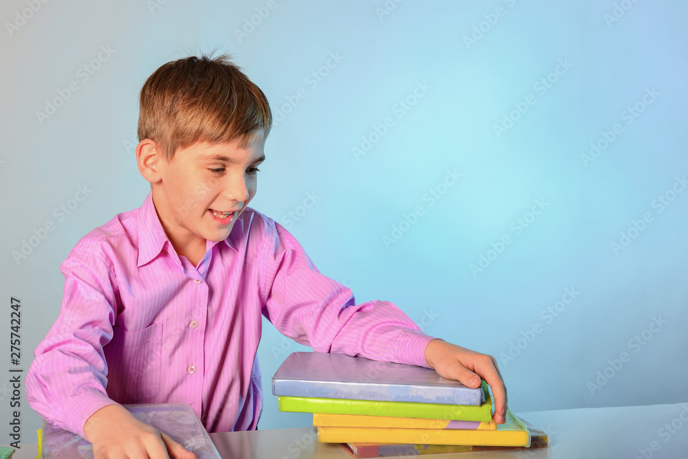 An inquisitive teenager hugs books while sitting at a desk. An inquisitive teenager hugs books while sitting at a desk.