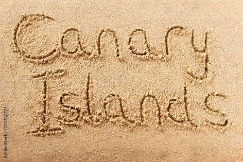 Canary islands word written in sand on a sunny spanish island summer beach holiday vacation travel destination sign writing message photo