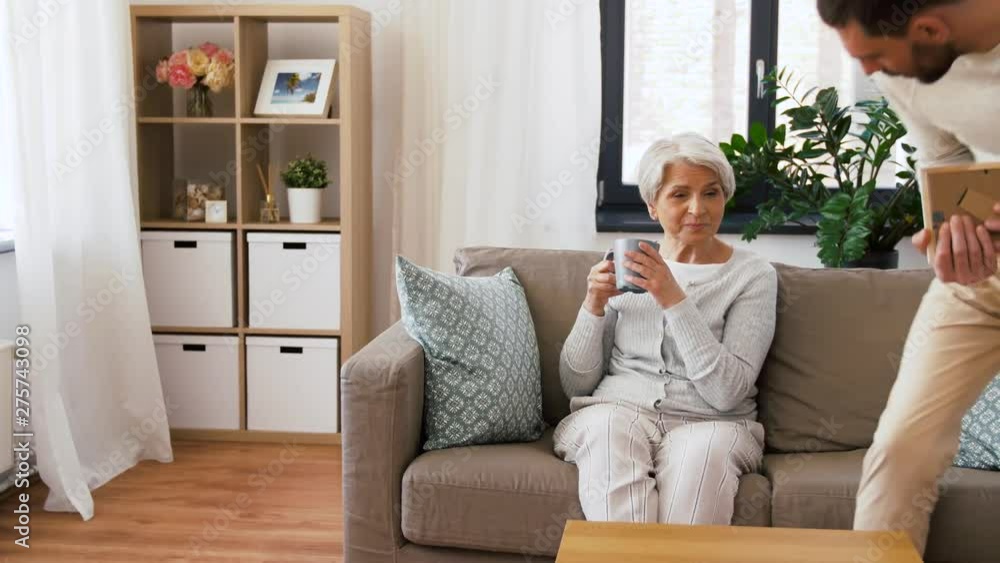 family, generation and people concept - happy smiling adult son and senior mother looking at photo at home family, generation and people concept - happy smiling adult son and senior mother looking at photo at home