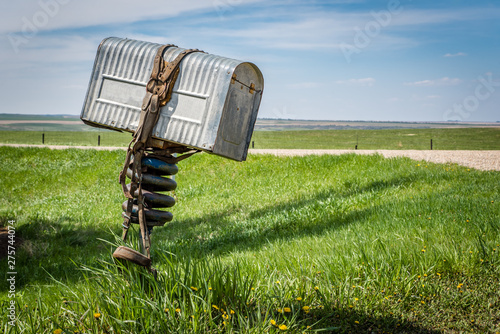 A rancher’s old metal mailbox with a bridle wrapped around it on the prairies in rural Saskatchewan, Canada