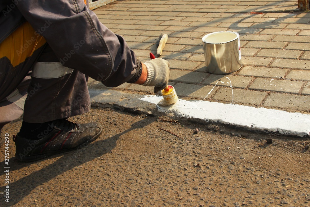 Man paints the border with white paint. city services Man paints the border with white paint. city services