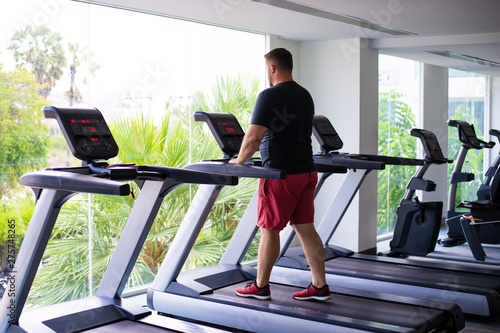 Wallpaper Mural chubby man walking on running track, warming up on gym treadmill. back view Torontodigital.ca