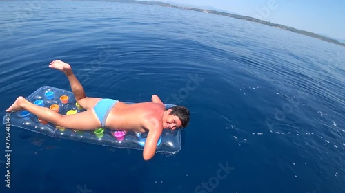 Summer on the Mediterranean deep blue sea young boy floating on an air mattress at summer vacation. Looking at the camera and smiling. Holiday, travel, people, adventure, tourism concept