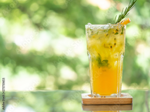 One glass of passion fruit soda serve on table in green garden background.