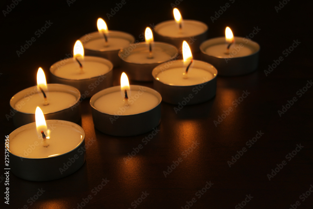 Burning candles on table in darkness. Romance, celebration and memorial symbol.