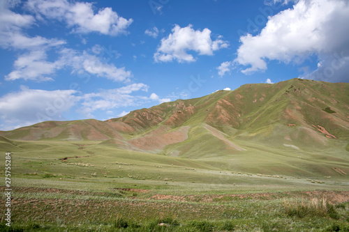 Pastures and green hills against the blue sky with clouds. Travel, Kyrgyzstan