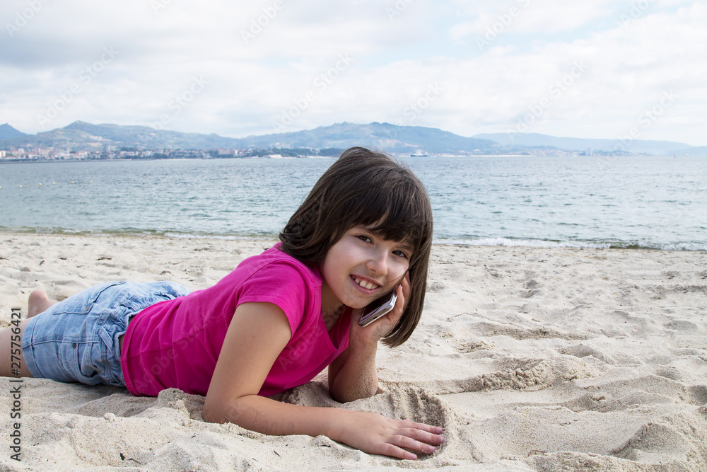 girl lying on the sand with the mobile phone girl lying on the sand with the mobile phone
