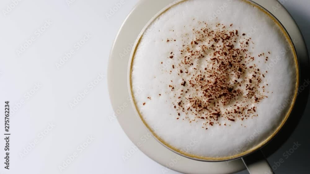 Hot coffee cup with frothed milk foam and chocolate decoration rotating on white background. Top view Hot coffee cup with frothed milk foam and chocolate decoration rotating on white background. Top view