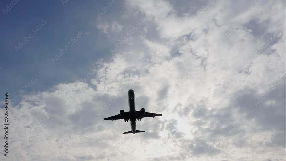 Slow motion tracking shot of a passenger airplane on a landing approach, silhouetted against the cloudy evening sky. Slow motion tracking shot of a passenger airplane on a landing approach, silhouetted against the cloudy evening sky.