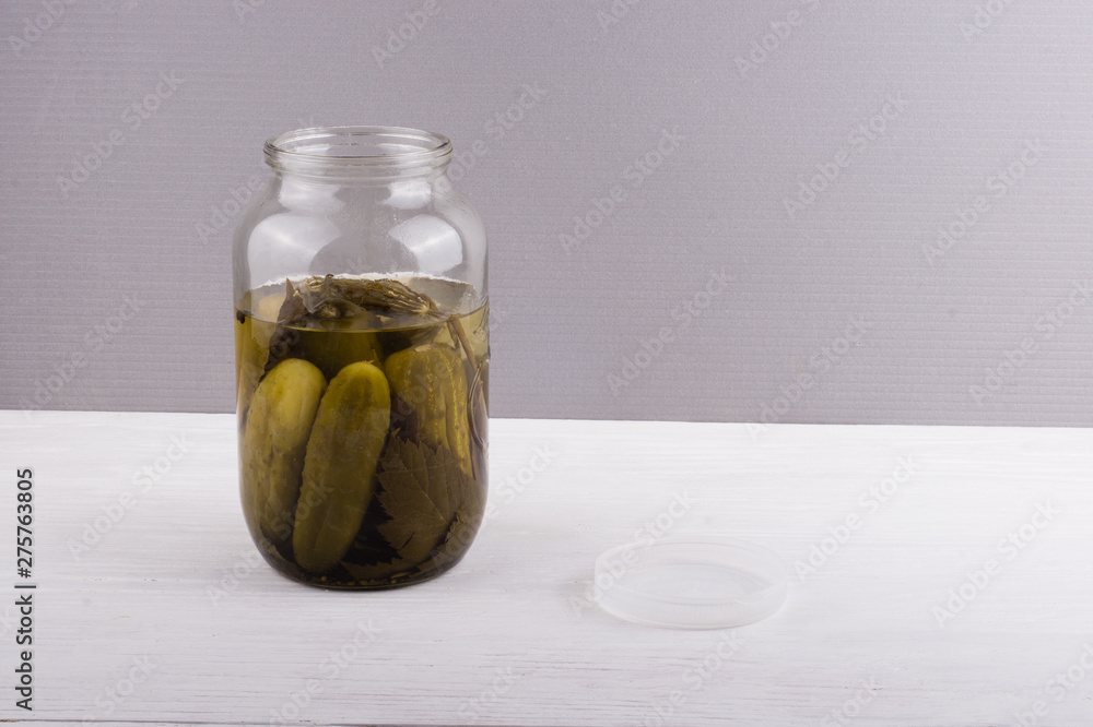 Glass jar with pickled cucumbers on gray background with copy space for text. Glass jar with pickled cucumbers on gray background with copy space for text.