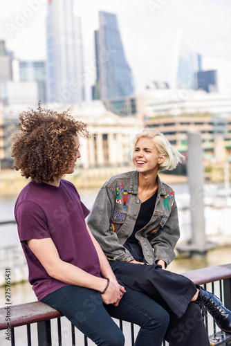 Happy couple talking sitting near River Thames.