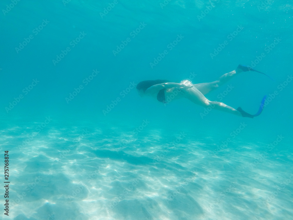 Fit girl in bikini freediving under the sea