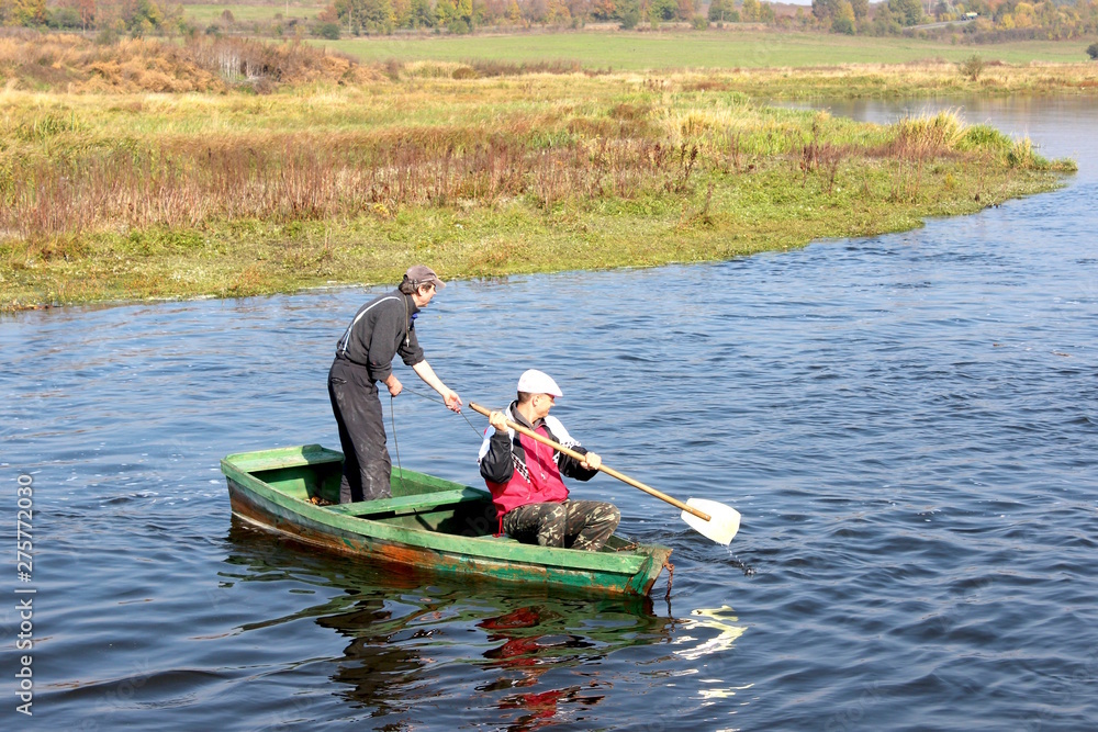 Two fishermen floating in a boat on the river Two fishermen floating in a boat on the river