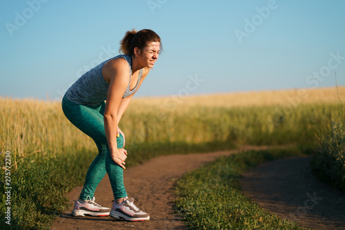 Fototapeta Naklejka Na Ścianę i Meble -  Young woman suffering from pain in her knee. Warm up before jogging, joints overload, sports trauma, health care