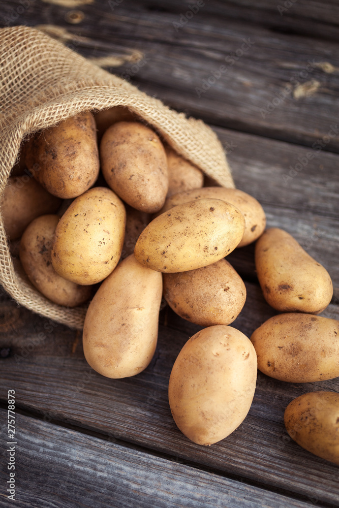 Raw potato food . Fresh potatoes in an old sack on wooden background Raw potato food . Fresh potatoes in an old sack on wooden background